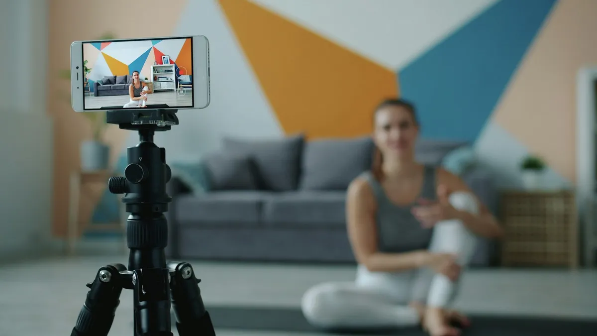 Yoga teacher recording a class on her phone with a tripod