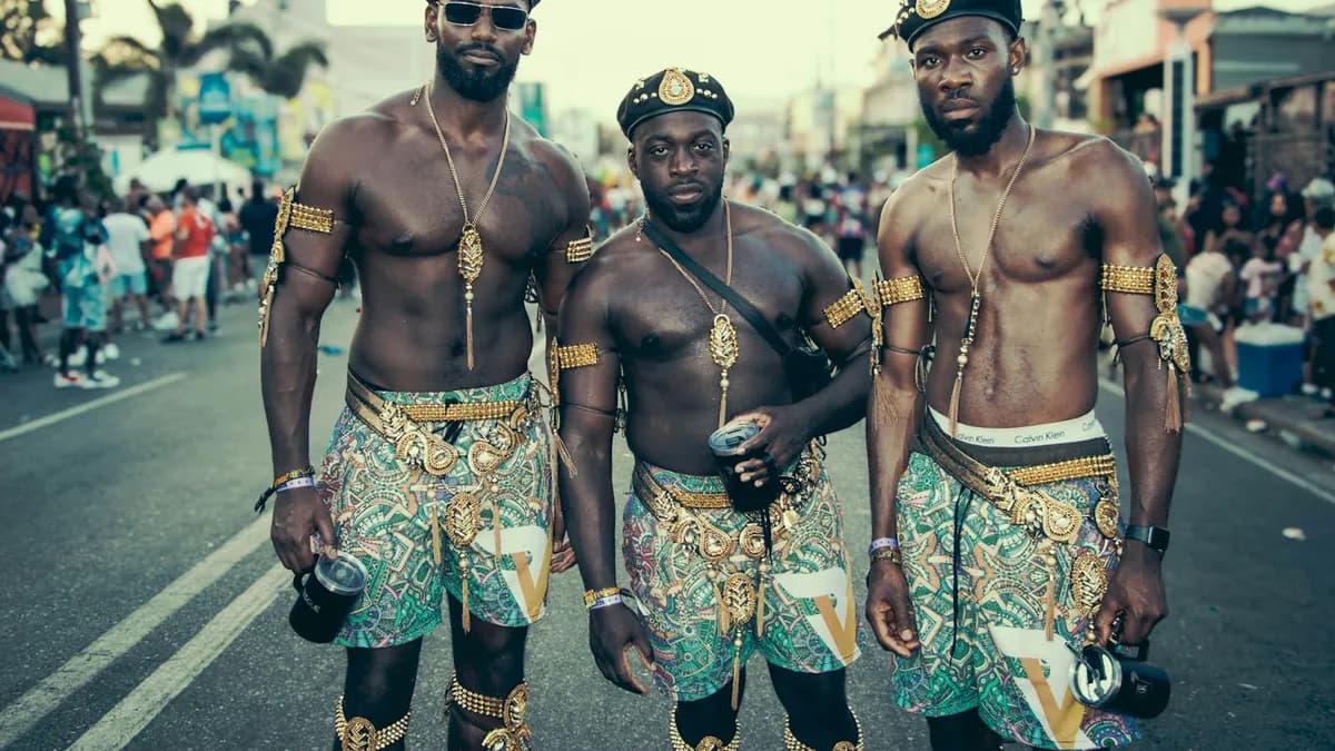 Three masqueraders in gold and teal costumes on the road at Trinidad Carnival