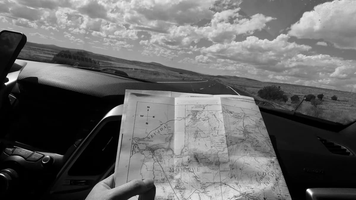 Paper road map of Nevada and Arizona held up against the windshield on a desert highway